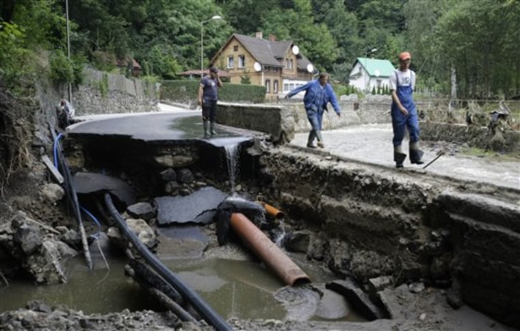 Residents walk past destroyed road after a flash floods hit the town of Bogatynia, Poland, Sunday, Aug. 8, 2010. The flooding has struck an area near the borders of Poland, Germany and the Czech Republic.(AP Photo/Petr David Josek)